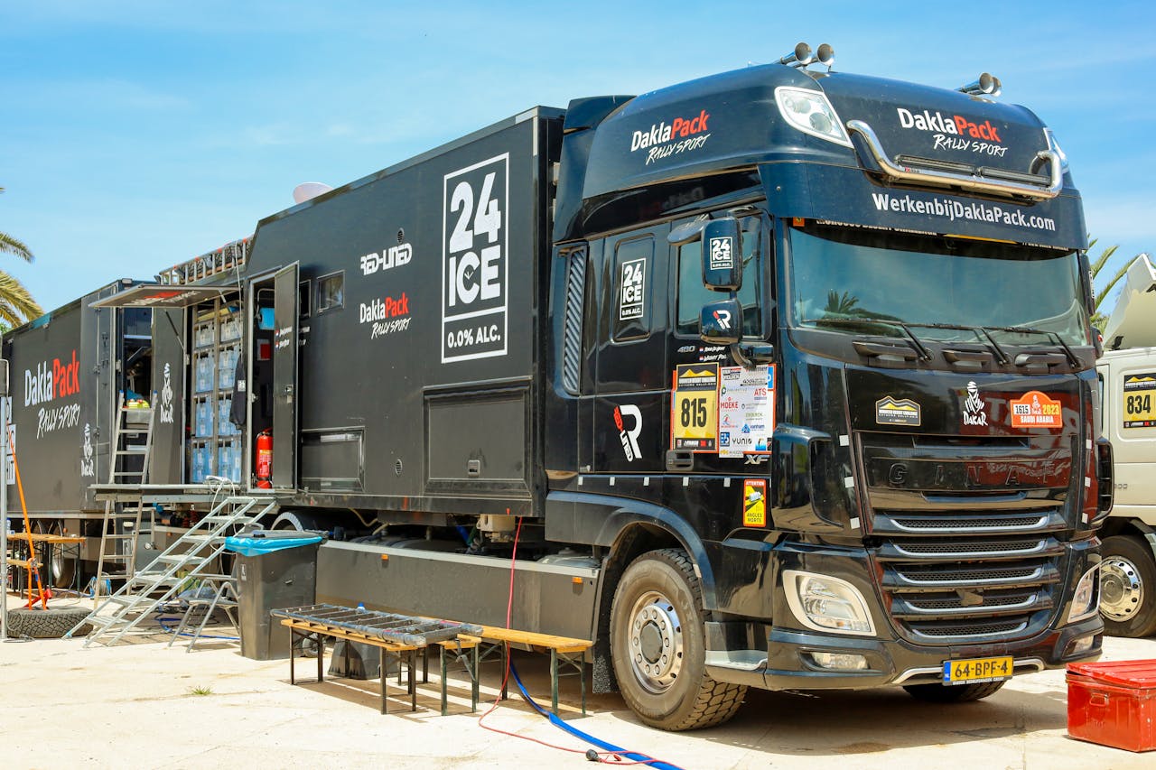 Services-01 Black DaklaPack rally truck with logos and equipment, parked outdoors on a sunny day.
